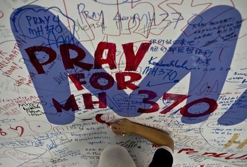 Un empleado de Malasyia Airlines, escribe un mensaje buenos deseos para los pasajeros del vuelo MH370. (Foto:AFP)