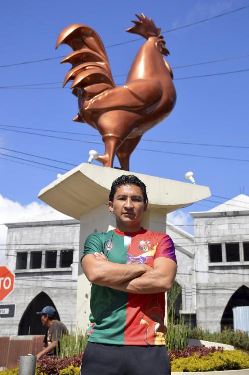 César Villaluz posó para Soy502 frente al Gallo, el monumento a la entrada del municipio. (Foto: Jenner Barrios/Colaborador)