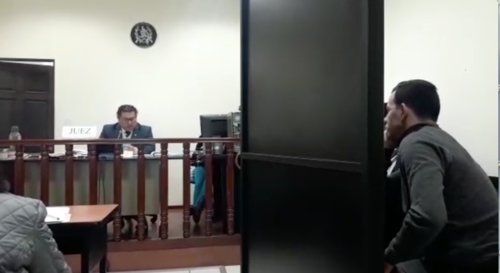 El juez Yubini Mérida explica la sentencia a Marco Pappa, quien todo el tiempo estuvo frente a un biombo que impedía el contacto físico y visual con la mujer agraviada, quien es su actual pareja. (Foto: captura de pantalla)