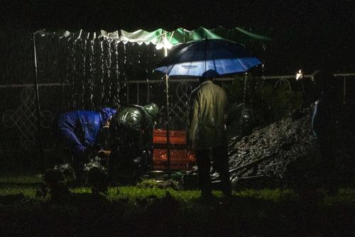 En medio de la tormenta, los sepultureros se dan prisa a depositar el féretro en la fosa. (Foto: AFP)