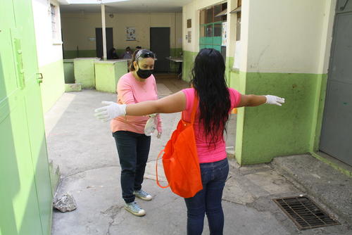 El personal educativo también participó en la sanitización de los padres de familia que ingresaron a la escuela de la colonia Lavarreda. (Foto: Soy502) 