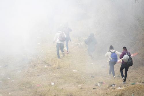 Migrantes se alejan del gas lacrimógeno. (Foto: AFP) 