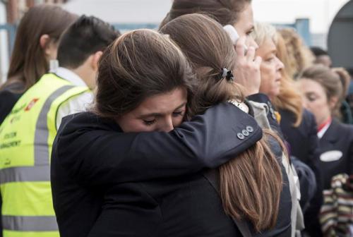 Dos trabajadoras del aeropuerto se abrazan mientras son evacuadas junto a los pasajeros de la zona. (Foto: EFE)