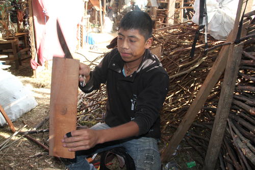 Elber Miza López corta un trozo de madera que utiliza como base para los pesebres que elabora con material que obtiene de las montañas de San Juan Comalapa, Chimaltenango. (Foto: Fredy Hernández/Soy502)