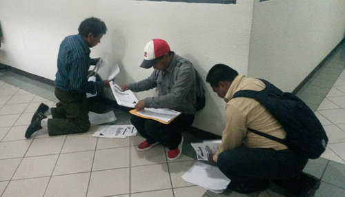 Candidatos a corporaciones municipales de Sololá preparan su papelería antes de entregarla en la ventanilla respectiva. Lo hacen en el suelo pues la CGC carece de un espacio adecuado para ello. (Foto: Soy502) 