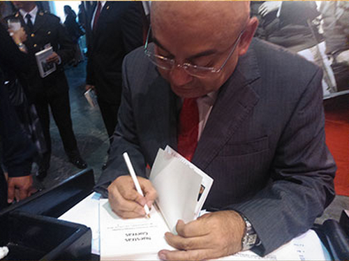 El Coronel Jorge Ortega firma la copia de uno de sus libros en Filgua 2013. (Foto: Archivo SCSPR)