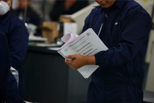 Uno de los trabajadores de la imprenta hace una revisión manual de las papeletas ya impresas. (Foto: Wilder López/Soy502)