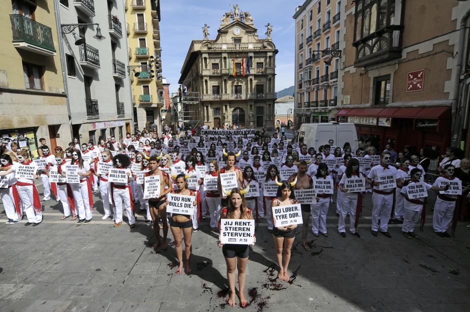 La mayoría de los participantes se han transformado en corredores, vestidos de blanco y rojo, pero con la cara pintada de blanco y negro y las manos de pintura roja, simbolizando la sangre. Delante de ellos varios activistas se han puesto en la piel del toro, con cuernos en la cabeza y pantalones negros. (Foto: AFP)&nbsp;&nbsp;