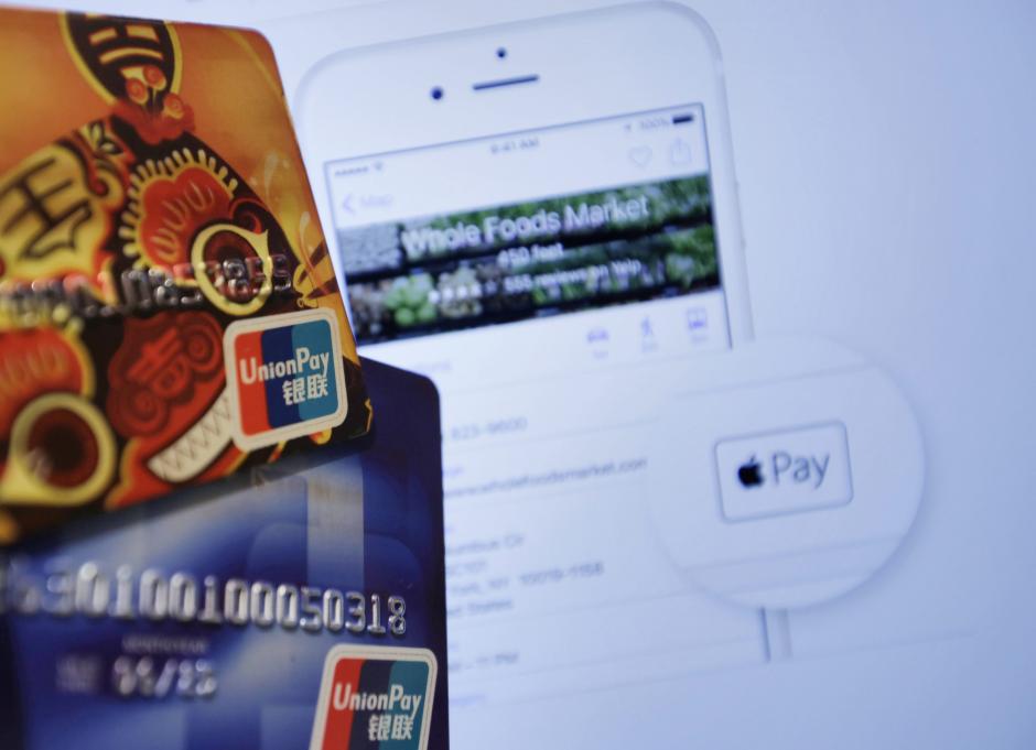 Fotografía que muestra varias tarjetas bancarias de UnionPay ante una pantalla de ordenador que muestra la página Web de Apple en China. (Foto: EFE)