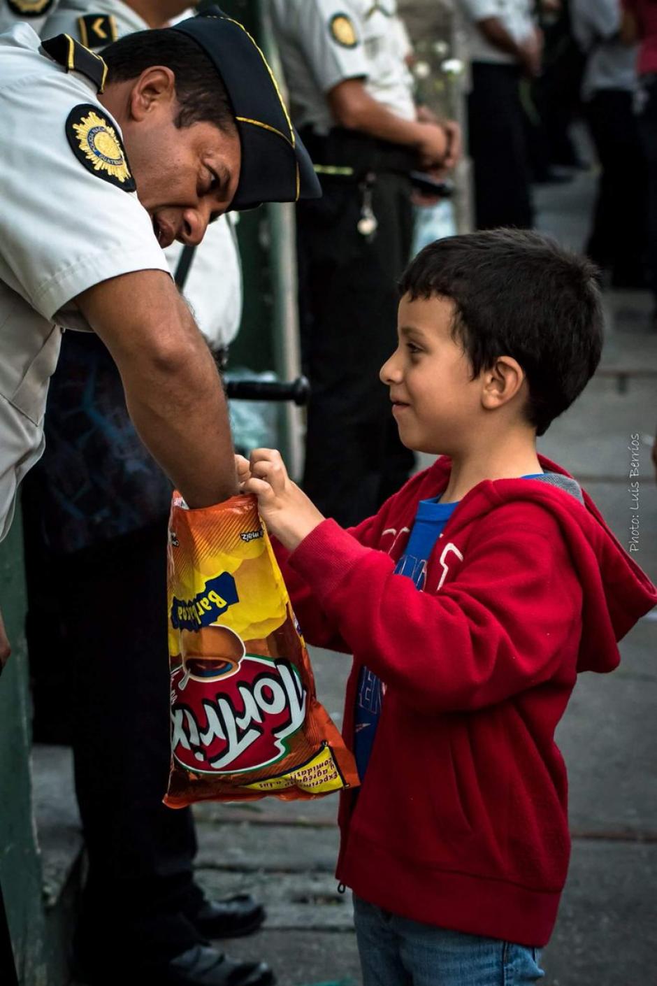 Un niño comparte una bolsa de frituras con un agente de la PNC. (Foto: Luis Berríos)