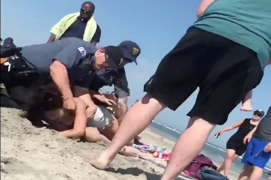 El policía golpeó el rostro de la mujer luego de lanzarla sobre la arena. (Imagen: captura de pantalla)