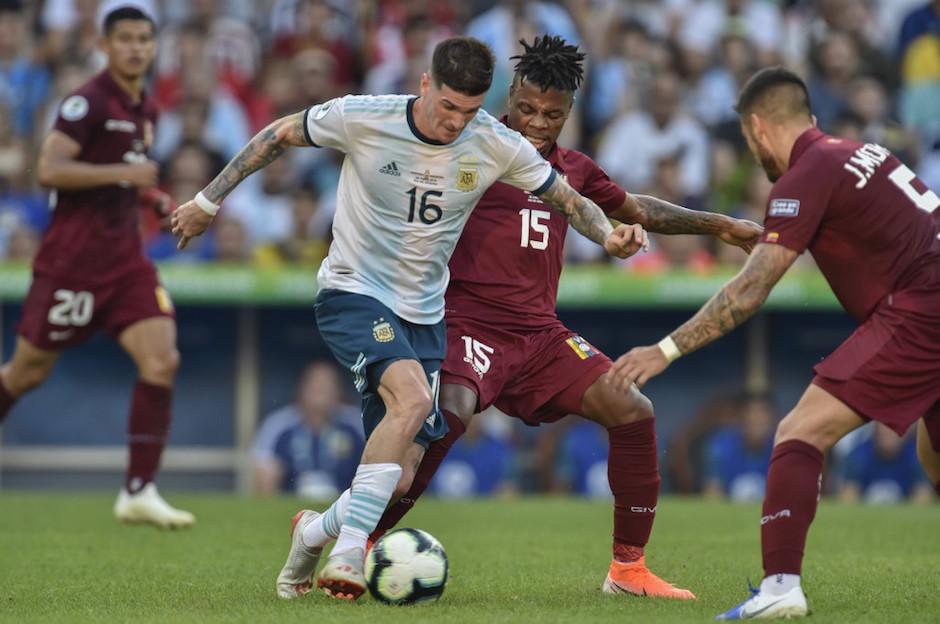 Rodrigo De Paul protege el balón ante la férrea marca de los venezolanos. (Foto: AFP)