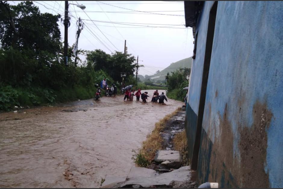 Personas tratan, con dificultad, de pasar hacia sus hogares en Amatitlán. (Foto: Conred)