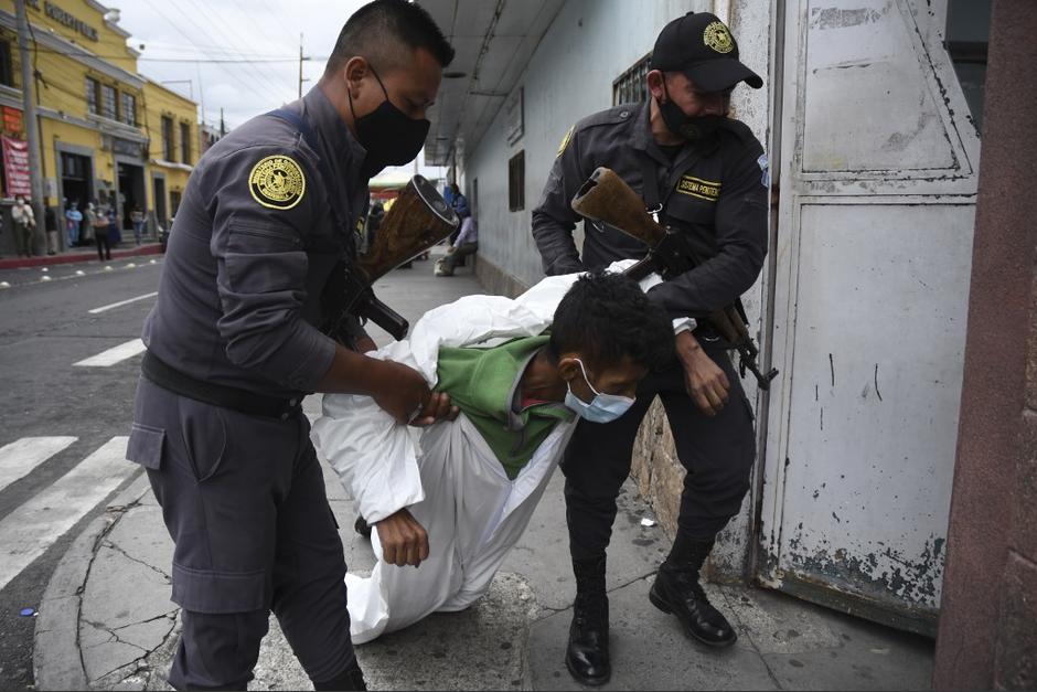 Guardias del Sistema Penitenciario (SP) arrastran a un privado de libertad hacia la entrada de emergencia del Hospital San Juan de Dios. (Foto: Johan Ordóñez /AFP)&nbsp;