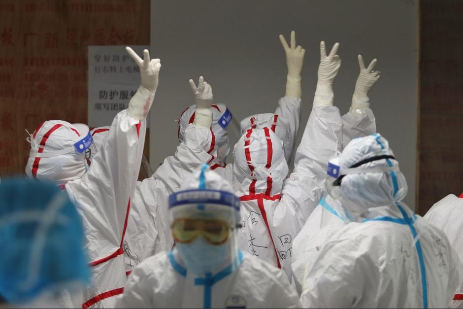 Personal médico se anima antes de ingresar a una sala con pacientes de covid-19 en un hospital de Wuhan. (Foto: AFP)&nbsp;