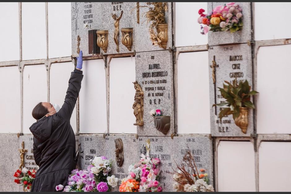 Una mujer que usa una máscara facial y guantes toca un nicho durante el entierro de un hombre que murió por el nuevo coronavirus en el cementerio municipal del sur de Madrid. (Foto: AFP)&nbsp;