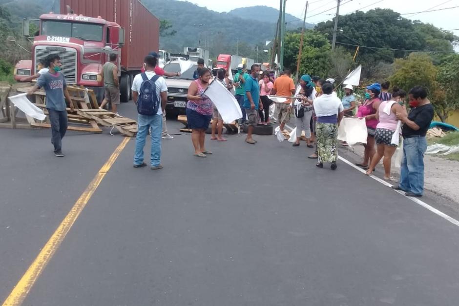 Con banderas blancas, un grupo de personas bloqueó la ruta al Pacífico en el área de "Balcones" en Palín, Escuintla. (Foto: Canal 46 News)&nbsp;