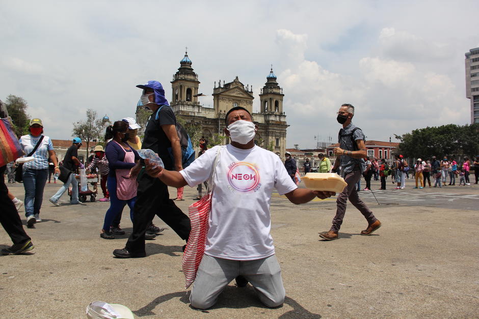 Un hombre se arrodilla tras recibir sus alimentos por parte de la Olla Comunitaria en la Plaza de la Constitución. (Foto: Fredy Hernández/Soy502)