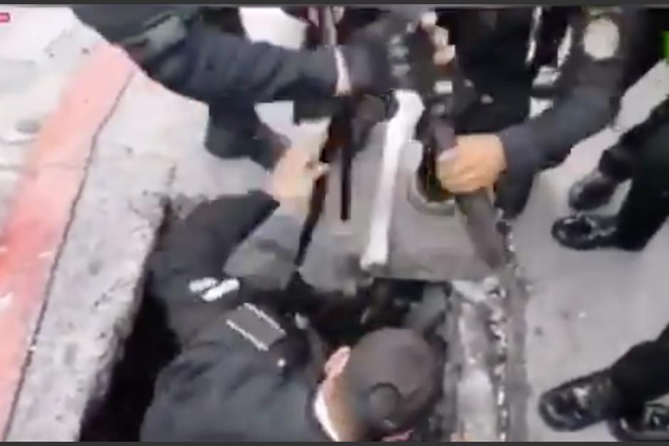 La PNC fue captada cuando sacaba armas de un tragante en la zona 1. (Foto: Captura de pantalla)