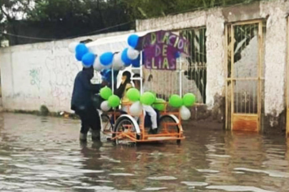 El padre empuja la bicicleta junto con su hijo que quedaron varados en medio una inundación. (Foto: Luna Méndez)