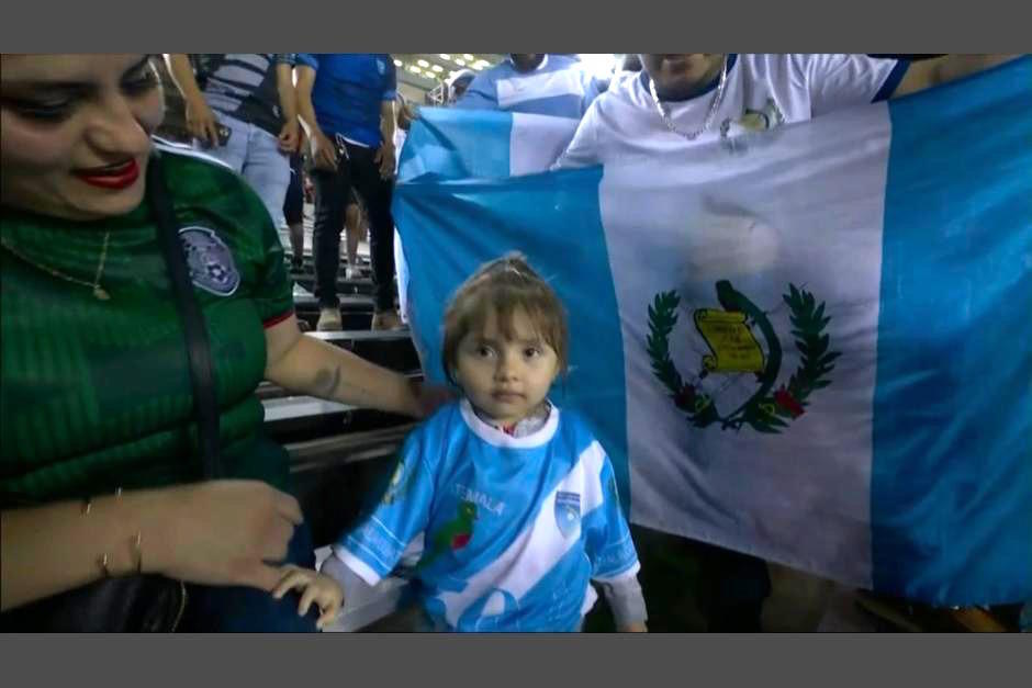 La madre se coloca la camiseta alusiva a la selección de Guatemala a su pequeña. (Captura Video)
