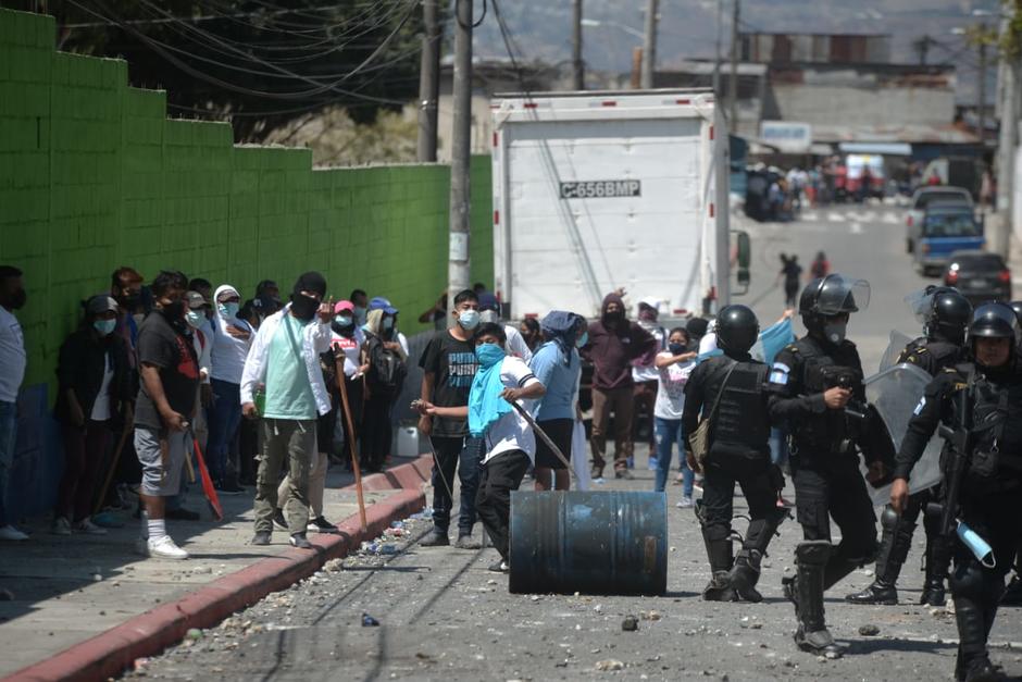 Momento en el que uno de los invasores lanza una piedra contra los vecinos de Nimajuyú, zona 21. (Foto: Wilder López/Soy502)
