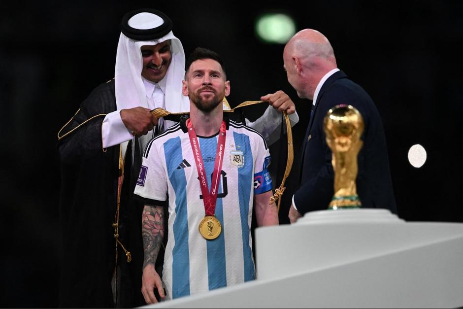 El emir jeque de Qatar, Tamim bin Hamad al-Thani, junto al presidente de la FIFA, Gianni Infantino, coloca una abaya a, Lionel Messi. (Foto: AFP)
