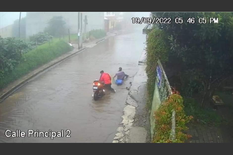 Dos personas quedaron atrapadas en la calle inundada por la lluvia del lunes en Santo Tomás Milpas Altas. (Captura Video)