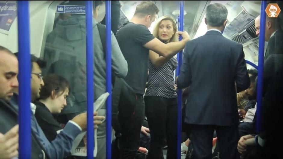 La mujer que iba parada en el metro empieza a sentirse incómoda cuando el hombre con la camiseta negra se le acerca demasiado. (Captura YouTube)