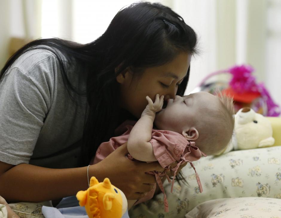 Pattharaomon Janbua, de 21 años, besa a su hijo biológico con síndrome de Down Gammy, de siete meses, en un hospital de la provincia de Chonburi (Tailandia). &nbsp;(Foto: EFE)