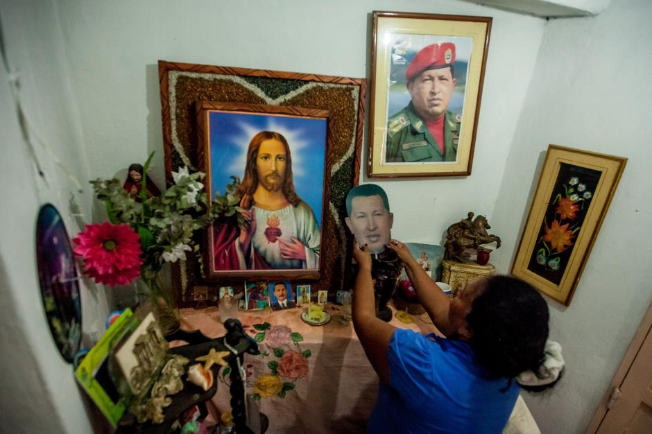 La venezolana Clemencia Linares arrelga una imagen del fallecido Hugo Chávez en el altar religioso en su vivienda, en Venezuela, donde la polémica ahora surge por el uso de la frase "Chávez nuestro". (Foto: EFE)&nbsp;