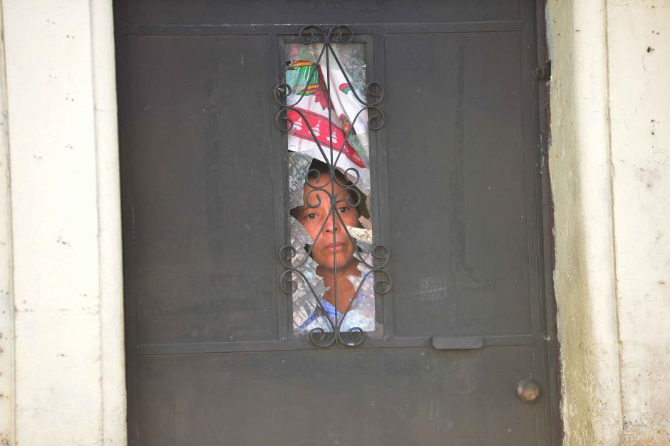 Una vecina del sector aledaño al Hospital General San Juan de Dios se asoma por la ventana que se rompió por la explosión de granada. (Foto: Jesús Alfonso/Soy502)&nbsp;