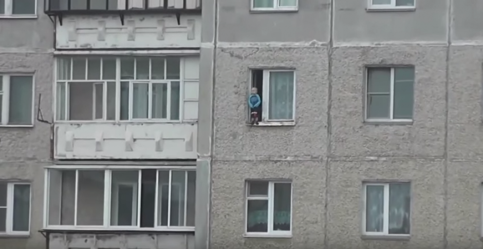 El niño se sentía cómodo observando hacia abajo en la cornisa de la ventana de un octavo piso. (Captura de YouTube)