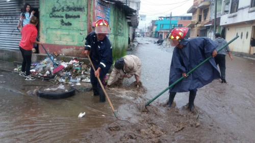 Bomberos ayudan a retirar basura de tragantes bajo la lluvia